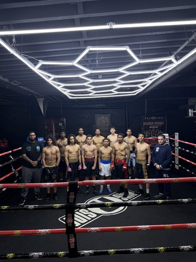The full amateur team standing in the ring with their coaches after a session.