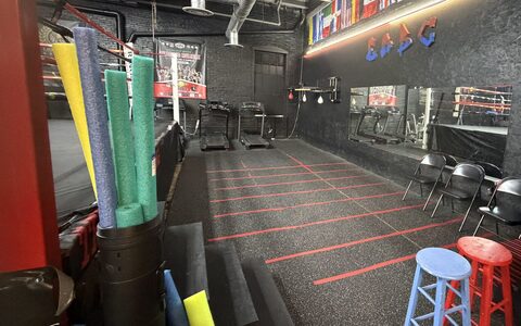The conditioning floor at East Reading Boxing Club: training lines marked out on the rubber, foam rollers and mats stacked against the black brick wall.