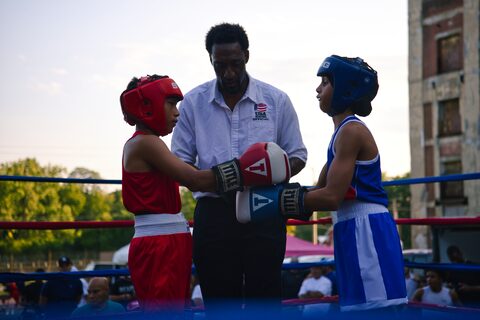 The referee giving final instructions as two young boxers touch gloves before the first round, red corner against blue.
