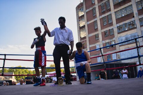 The referee raising a young fighter's arm at the end of a bout.